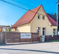 A family house on Sklárska Street in Lednické Rovne with a red roof and a wooden fence.