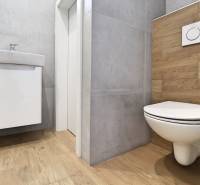 A toilet with a wooden-patterned floor and a simple sink in a family house.