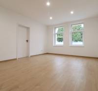 A spacious room with a wooden decor floor and white walls in a family house.