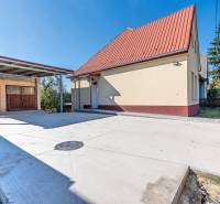 A family house on Sklárska Street in Lednické Rovne with adjacent buildings and a paved area.