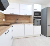 A kitchen in a 4-room apartment with modern appliances, wood-patterned flooring, and light-colored cabinets.