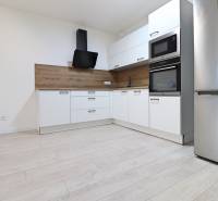 A kitchen with built-in appliances and a wooden decor floor in a 4-room apartment.