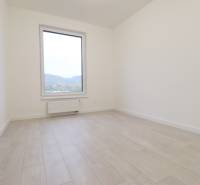 A bright room with a wall and a large window, wooden decor flooring in a 4-room apartment.