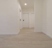 A hallway in a 4-room apartment with white walls and a floor with a wooden decor.