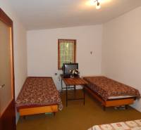 The cottage offers two beds with embroidered blankets and a small television on the table.