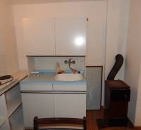 A kitchenette in a cottage with a two-burner stove, a sink, and a stove, without wooden decor.