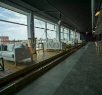 Spacious gastro spaces with wood-patterned flooring and large windows.