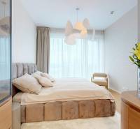 A bright bedroom with curtains, a bed, an original light fixture, and flowers in a 4-room apartment.