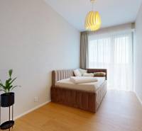 Bedroom in a 4-room apartment with a light-colored bed and a plant on the floor with wooden decor.