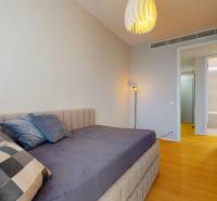 A bedroom with a sofa, wood-patterned flooring, and open doors in a four-room apartment.