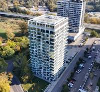 A high-rise building on Krasovského Street in Bratislava - Petržalka, surrounded by greenery and a parking lot.