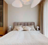 Bedroom in a 4-room apartment with a bed, wardrobe, and lamps, floor with wooden decor.