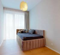 A room with a light wall, a bed, curtains, and a floor with a wooden decor in a 4-room apartment.