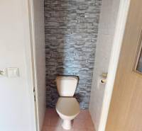 A toilet with stone-like tiles in a 4-room apartment.
