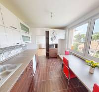 A kitchen in a 4-room apartment with a wooden decor floor, a large window, and white furniture.