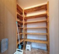 A pantry in a 4-room apartment with wooden shelves and tiled flooring.