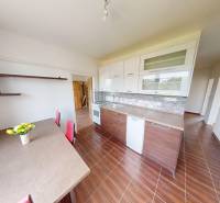 The kitchen of a 4-room apartment with a wooden decor floor, a dining table, and cabinets.