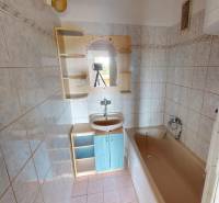 A bathroom in a 4-room apartment with a bathtub, sink, and cabinet.