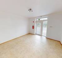 Interior of a family house with white walls, a French window, and a cream floor.