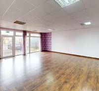 A spacious room in a family house with a wooden decor floor and floral wallpaper.