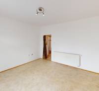 A room in a family house with white walls, a heating unit, and two doors.