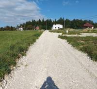 The road on Stránska Street with residential plots, surrounded by houses and greenery.