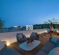 A terrace with a view of the city, comfortable seating, and people exercising in a 3-room apartment.