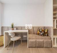 A workspace with a chair, table, bench, and shelves in a 3-room apartment.