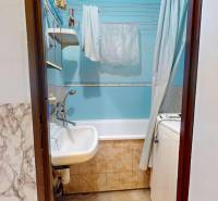 Bathroom in a 3-room apartment with a bathtub, sink, and washing machine, blue walls, drying rack.