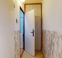 A narrow hallway with a tiled floor, doors to the bathroom, in a 3-room apartment.