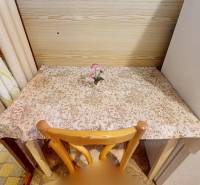 A kitchen table with a flower on a tablecloth-covered top in a 3-room apartment.