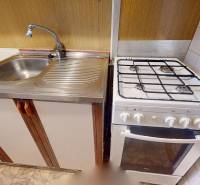 A kitchen in a 3-room apartment with a stainless steel sink and a gas stove.
