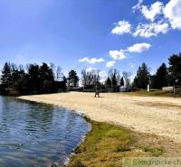 The beach near the cottage in Malé Leváre surrounded by greenery and a blue sky.