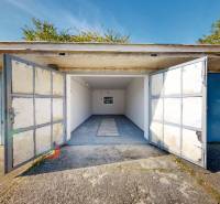 Open garage on Akademika Jozefa Čabelku Street in Holíč with a concrete floor and blue doors.