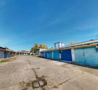 Garages on Akademika Jozefa Čabelku Street in Holíč with blue doors and a concrete road.