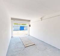 An empty garage with a concrete floor and open doors on Akademika Jozefa Čabelku Street in Holíč.