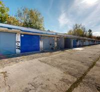 Garages on Akademika Jozefa Čabelka Street in Holíč, surrounded by trees, a bicycle by the wall.