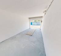 An empty garage with a concrete floor and white walls.