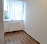 A simple room in a 3-room apartment with a wooden decor floor.