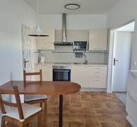 A kitchen in a 3-room apartment with a ceramic floor, a table, and chairs.