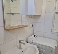 A bathroom in a 3-room apartment with a sink, cabinet, and washing machine.