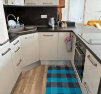 A kitchen in a 3-room apartment with a kitchen unit, sink, and floor with a wooden decor.