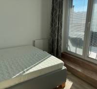 A bright bedroom with a bed and a French window in a 3-room apartment.