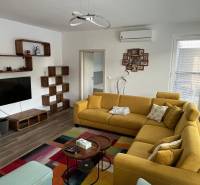 Living room in a two-room apartment with a wooden decor floor and a yellow sofa.