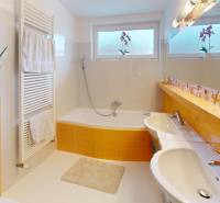 A bathroom in a family house with yellow tiles, a bathtub, and two sinks.