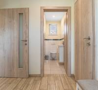 A hallway in a family house with a view into the bathroom, wooden doors, and tiles.