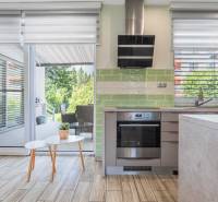 A kitchen in a family house with patio doors, green tiles, an oven, and a range hood.