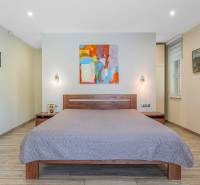 A bedroom in a family house with a wooden decor floor and an abstract painting.