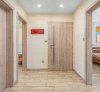 Hallway of a family house with wooden doors, a painting, and entrances to rooms.
