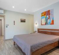 A bedroom in a family house with light walls, a wooden bed, and an abstract painting.